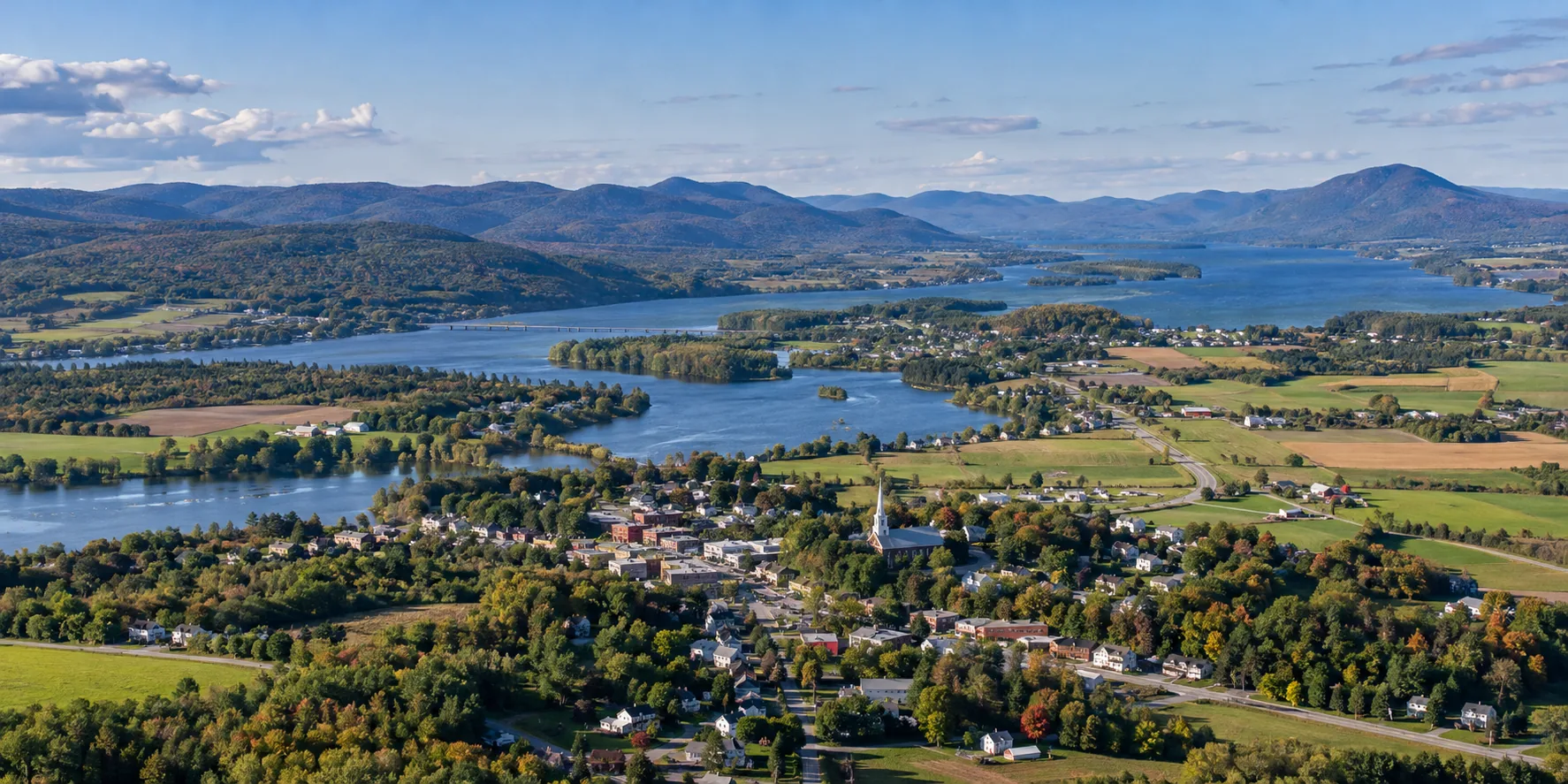 Paysage régional avec une municipalité, des terres agricoles, un lac et des montagnes